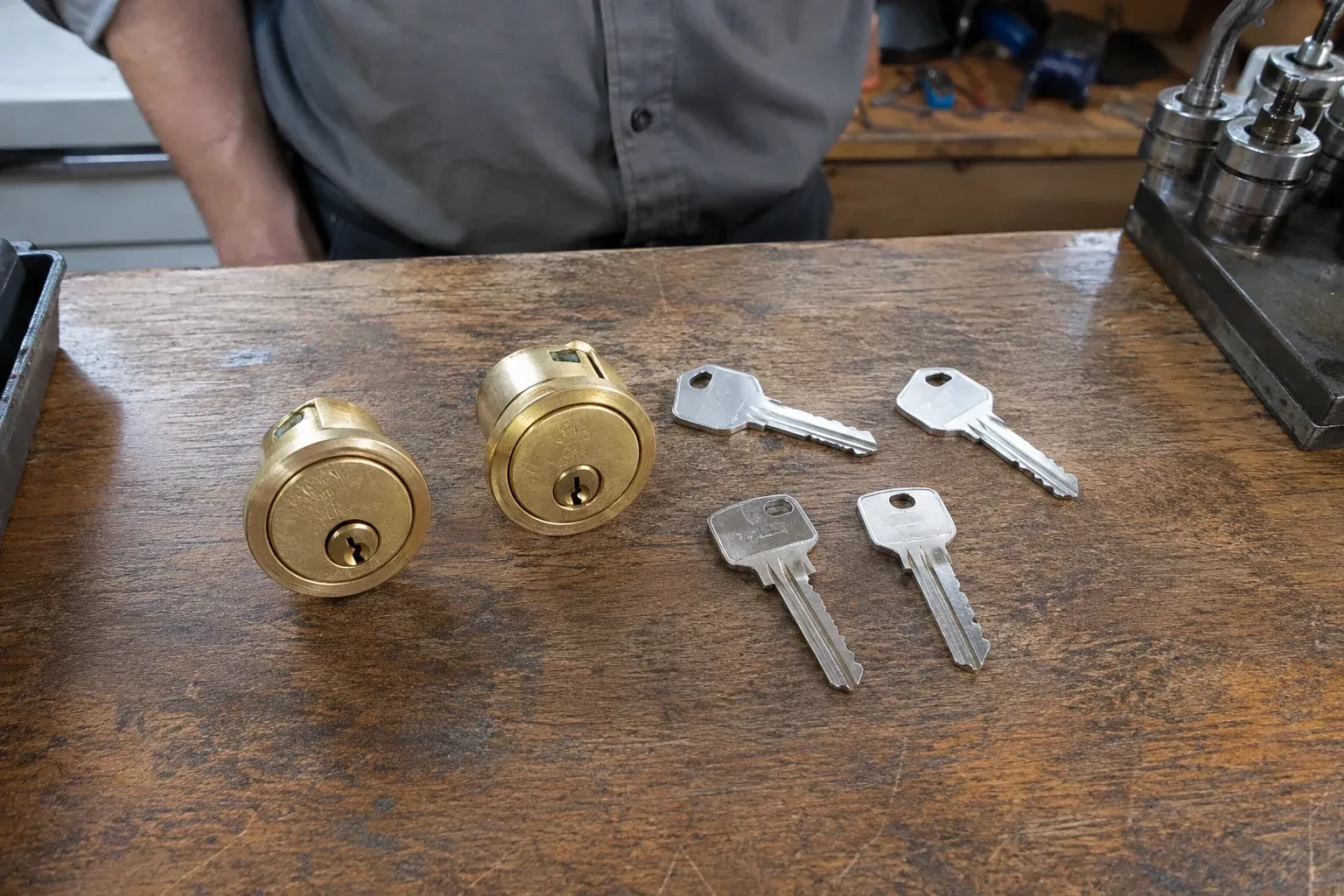 Two detached brass lock cylinders and four house keys on a wooden counter. — Lock Rekeying, Brampton